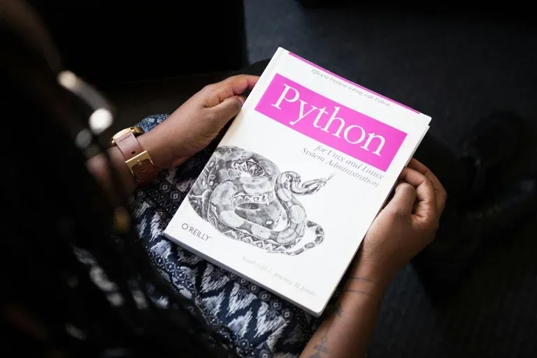 Input image — a person holding an O'Reilly Python book