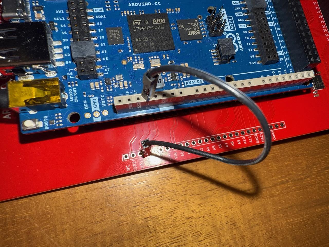 Close-up of the USB connection end of the Arduino Giga R1 mounted on the level converter shield, showing the jumper wire connecting 3.3V power between boards