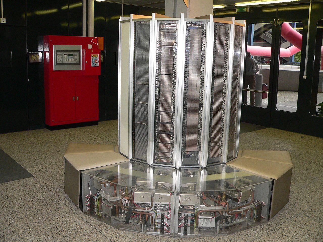 A Cray-1 supercomputer on display, showing its distinctive cylindrical tower design with bench seating and exposed cooling plumbing